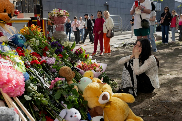 Une jeune femme pleure devant un mémorial improvisé près d'un immeuble résidentiel partiellement détruit à Kyiv, le 15 mai 2026 en Ukraine