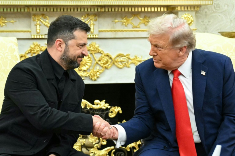 Le président américain Donald Trump (d) serre la main de son homologue ukrainien Volodymyr Zelensky lors d'une rencontre dans le Bureau ovale à la Maison Blanche, le 18 août 2025 à Washington
