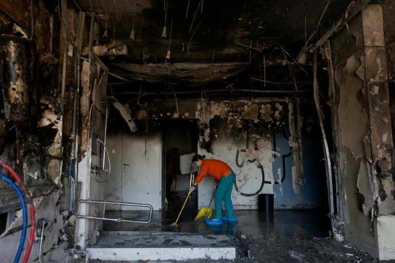 Une femme dégage des débris après l'attaque par des drones d'une clinique privée à Kiev, le 5 janvier 2026, en Ukraine