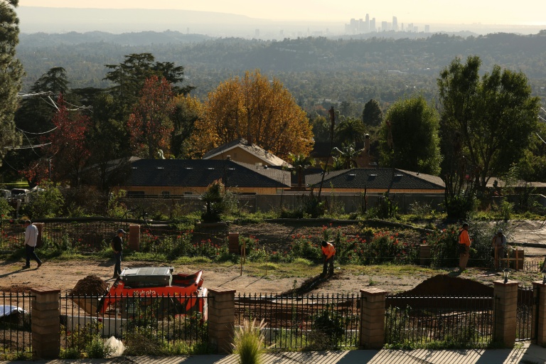 Des ouvriers creusent les fondations d'une maison à Altadena, avec à l'horizon les tours du centre-ville de Los Angeles, le 29 décembre 2025 