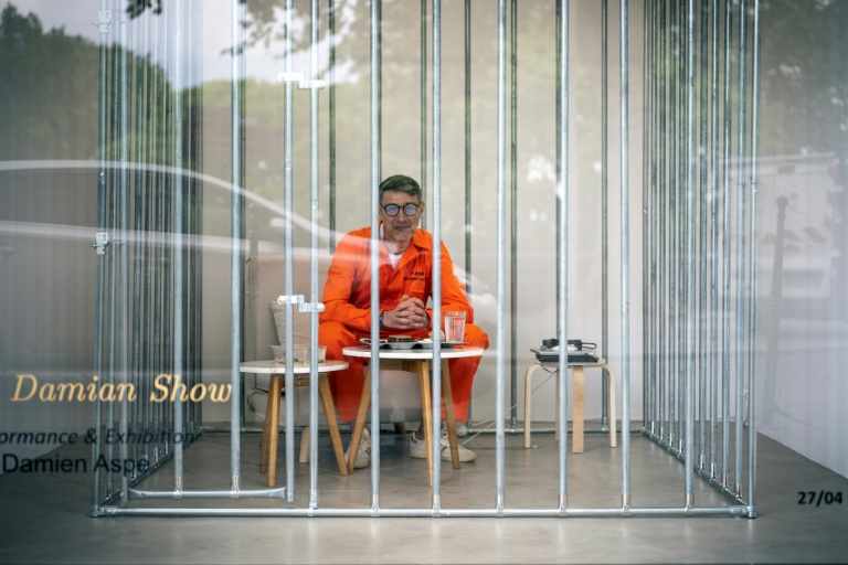 L'artiste Damien Aspe visible à travers la vitrine de sa galerie, où il s'est enfermé dans une cage pour dénoncer l'emprise des GAFAM, le 28 avril 2028 à Toulouse