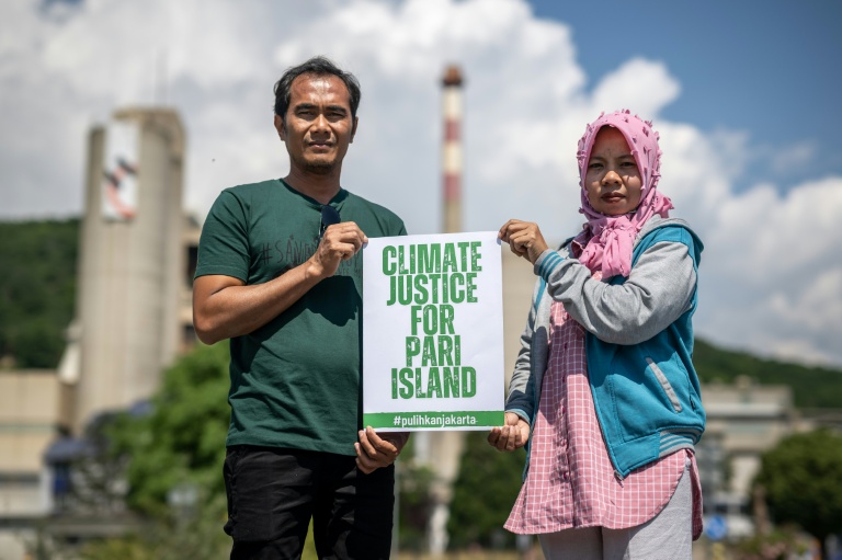 Edi (g) et Asmania, deux habitants de l'île indonésienne de Pari, posent pour une photo le 11 juin 2023 à côté de l'usine du géant suisse du ciment Holcim à Eclepens, dans l'ouest de la Suisse