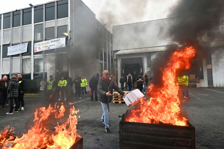 Un employé brûle des documents devant l'usine Brandt à Vendôme, le 11 décembre 2025 dans le Loir-et-Cher