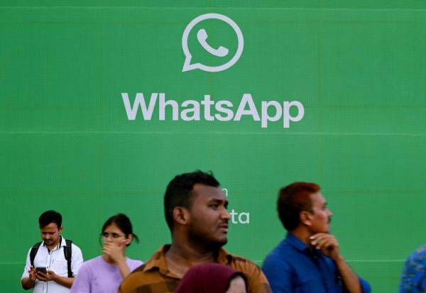 Des touristes devant une publicité pour l'application de messagerie Whatsapp, à Bombay le 25 août 2023