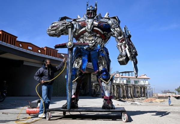 Le sculpteur Ehtisham Jadoon à côté de son Optimus Prime, personnage du film Transformers, fabriqué à partir de ferraille devant son atelier situé à la périphérie d'Islamabad, le 12 février 2026 au Pakistan