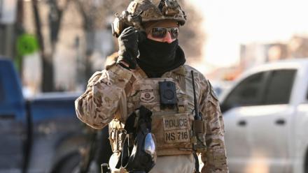 Un agent de la police aux frontières américaine devant des manifestants à Minneapolis, près du lieu où des agents fédéraux ont tué un homme par balle, le 24 janvier 2026