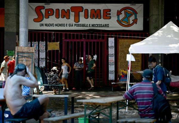 Des personnes récemment expulsées d'un centre social à Rome sont installées devant ses grilles fermées, le 11 août 2026