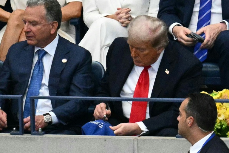 Le président américain Donald Trump (d) signe une casquette alors qu'il assiste à la finale de l'US Open entre l'Espagnol Carlos Alcaraz et l'Italien Jannik Sinner, à New York, le 7 septembre 2025