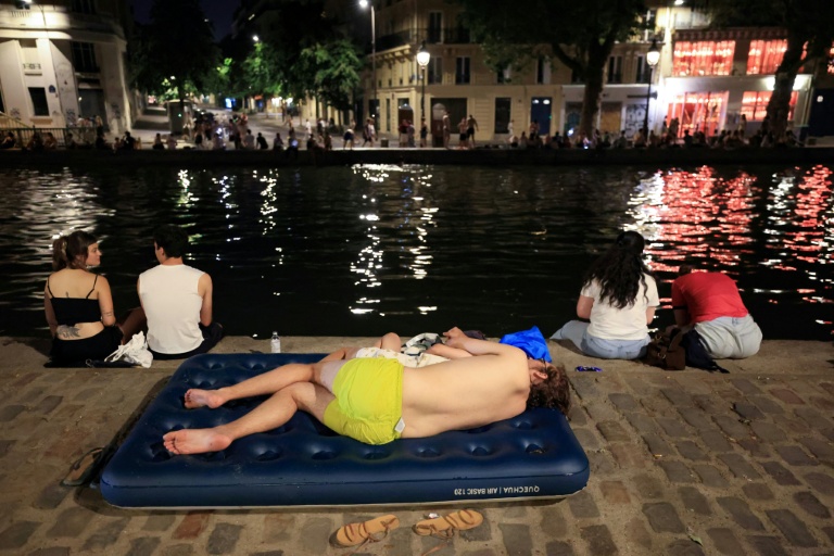 Un jeune se rafraïchit le long du canal Saint-Martin en pleine canicule à Paris le 25 juin 2026
