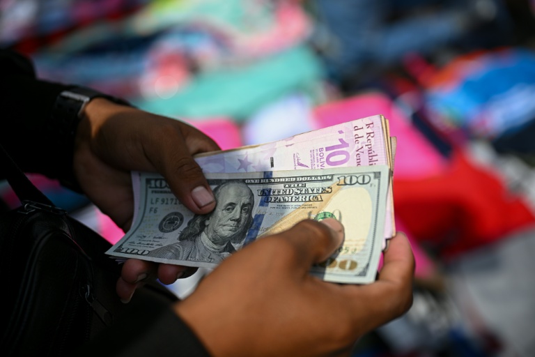 Un vendeur compte des billets de bolivars vénézuéliens et de dollars américains au marché de La Hoyada à Caracas, le 23 décembre 2025