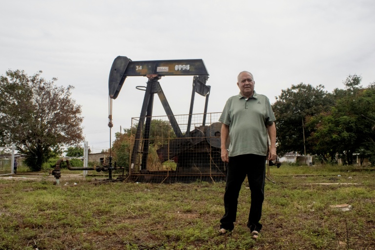 José Gregorio pose devant un chevalet de pompage à Bachaquero, près du lac de Maracaibo, berceau de l'exploitation pétrolière vénézuélienne